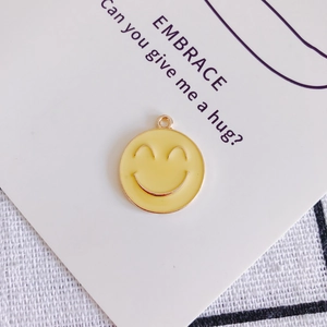 Vista macro del ciondolo emoji sorridente in smalto giallo per creazione gioielli DIY