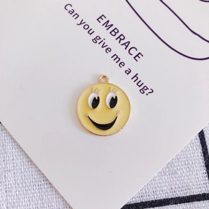 Dettaglio di un ciondolo emoji giallo con bordo dorato e finitura in smalto per gioielli fai-da-te