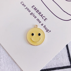 Vista macro di un ciondolo emoji giallo in lega con sorriso nero e gancio a scatto