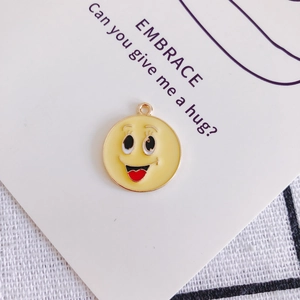 Dettaglio macro del ciondolo emoji giallo con lingua a cuore rosso per gioielli fai da te