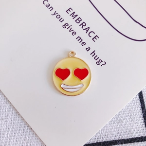 Dettaglio ravvicinato di un ciondolo emoji con occhi a cuore in smalto giallo e oro