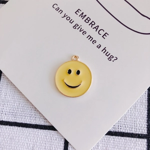 Dettaglio macro di un ciondolo emoji sorridente giallo con anello dorato per gioielli fai-da-te