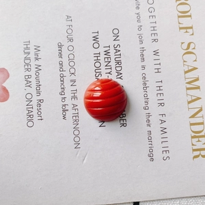 Close-up of bright red ribbed round resin bead accessory for DIY crafts and shoe charms