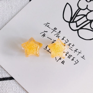 Close-up of star-shaped acrylic resin pendants with gold glitter in bright orange