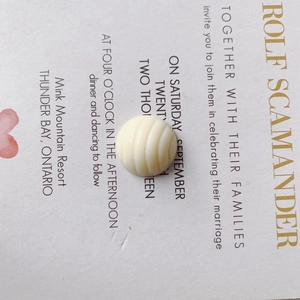 Macro detail of cream-white round resin bead with spiral texture for DIY crafts