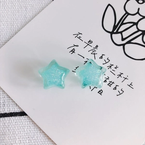 Macro view of light blue acrylic star earrings with fine glitter and translucent finish