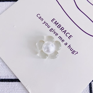 Macro-opname van een heldere hars madeliefje met grote parel in het midden voor DIY-haarclips