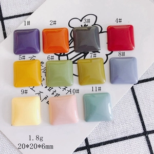 Flat lay of 20mm square candy-colored resin cabochons in 11 vibrant matte shades