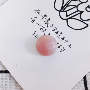 Close-up of polished round rose quartz stone bead with natural texture on a white card
