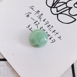 Close-up of a smooth round cabochon bead in pale green jade stone for DIY accessories