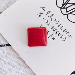 Glossy red square resin charm flat lay on white decorative card for DIY crafts
