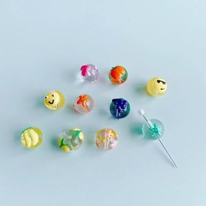 Gros plan de perles en verre peintes à la main avec motifs fruits et étoiles pour bijoux DIY