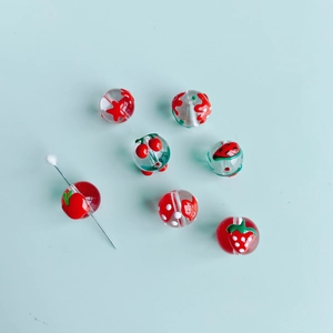 Vue détaillée de perles en verre aux motifs de fraises et cerises pour bijoux DIY
