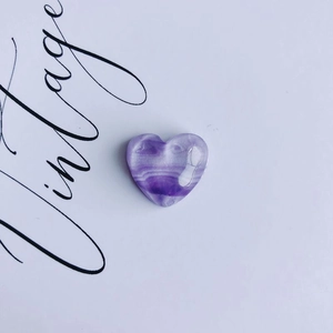 Macro shot of polished heart-shaped purple fluorite stone with natural wavy band texture