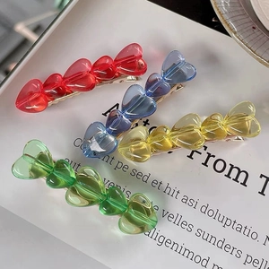 Detailed view of colorful heart-shaped resin hair clips with golden metal duckbill clips