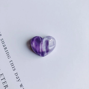 Dettaglio macro di un ciondolo a cuore in resina viola con trama artistica a vortice