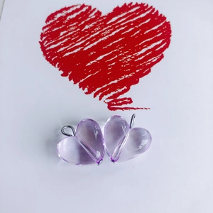 Detail of two light purple heart-shaped resin charms with silver metal loops on white