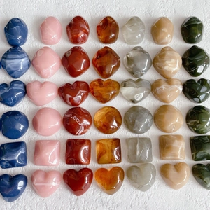 Macro view of assorted square and round resin charms with marble texture for DIY jewelry