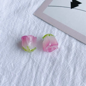 Vue macro de breloques boutons de rose en résine rose avec calice vert pour bijoux DIY