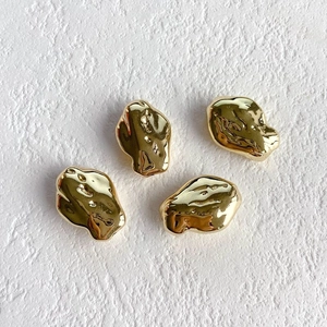 Close-up of four irregular gold plated resin beads with lava texture for DIY jewelry
