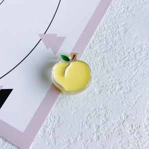 Dettaglio di un ciondolo a pesca in acrilico giallo con foglia verde per accessori DIY