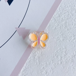 Gros plan d'un accessoire pour cheveux papillon en résine avec détails jaune et rose