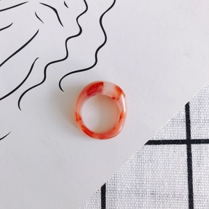 Detail of red and white marble pattern resin ring on minimalist textured background