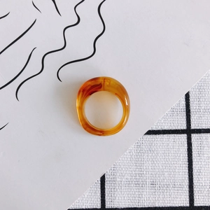 Macro detail of amber resin ring featuring organic tortoiseshell texture on graphic background