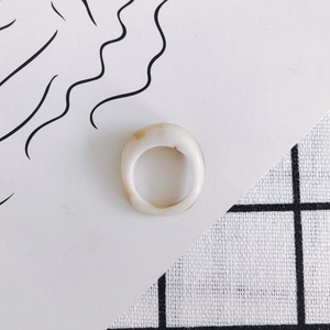 Detail shot of wide cream resin ring with light brown marble texture on plaid background