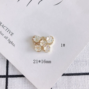 Detailed view of 21x16mm gold butterfly pendant with rhinestones and white shell flowers