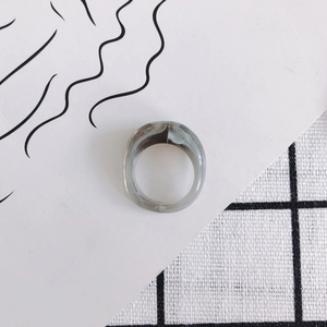 Close-up of a minimalist resin ring with grey and white marble texture on a card