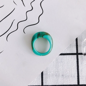 Macro shot of turquoise resin ring with artistic ink texture on minimalist card