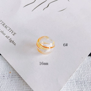 Macro detail of 16mm clear glass hollow bead with orange and yellow spiral swirl pattern