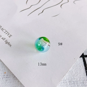 Macro view of 13mm hollow glass bead with blue and green swirl pattern details