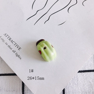 Détail de la perle en céramique verte 26x15mm avec points rouges et trou pour bijoux DIY
