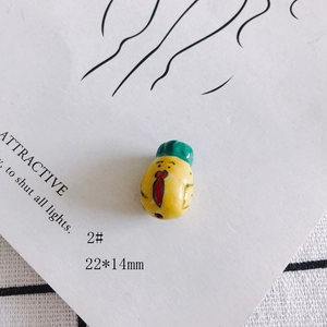Détail de la perle en céramique jaune de 22x14mm avec petit personnage dessiné