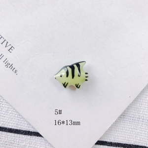 Detail view of a 16x13mm yellow ceramic fish bead with black stripes for DIY jewelry making