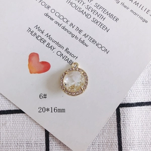 Detalle de un colgante redondo dorado de 20x16mm con circón claro y diamantes rosas