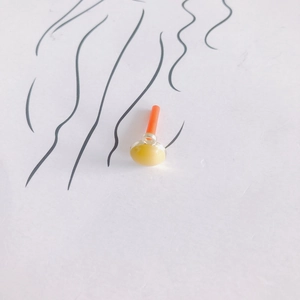 Detailansicht gelber Ohrring-Anhänger mit orangefarbenem Stift auf künstlerischem Hintergrund