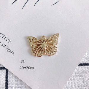 Détail d'un pendentif papillon doré 29x20mm avec texture creuse et perle incrustée