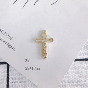 Détail macro d'un pendentif croix dorée 29x18mm orné de cinq zircons cubiques ronds