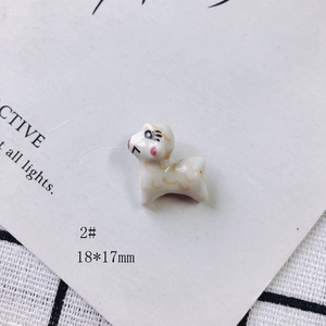 Detailed view of white ceramic sheep charm with gold wavy patterns, 18x17mm size