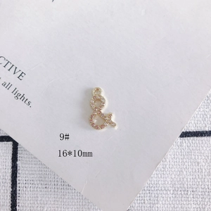 Détail macro d'un pendentif esperluette doré 16x10mm orné de strass roses et blancs