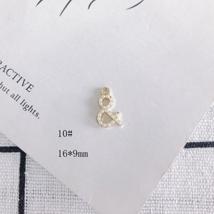Détail d'un pendentif esperluette doré de 16x9mm avec perles blanches pour bijoux DIY