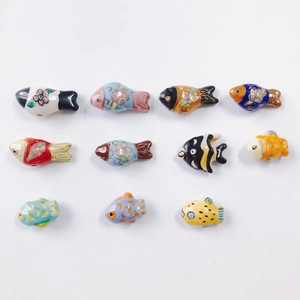 Detailed view of eleven colorful handmade ceramic fish beads for DIY jewelry making