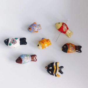 Macro detail of handmade colorful ceramic fish beads with holes for DIY jewelry