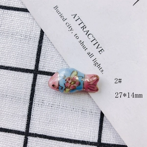 Macro view of handmade pink and blue ceramic fish pendant with flower pattern 27x14mm