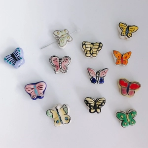 Detailed view of colorful butterfly ceramic beads with hand-painted textures for DIY crafts