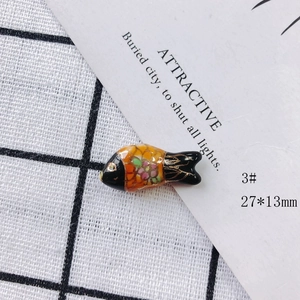 Macro view of a 27x13mm fish-shaped ceramic charm with colorful floral patterns