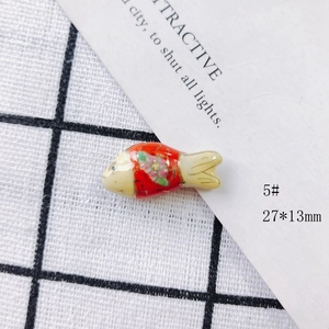 Macro shot of 27x13mm red handmade ceramic fish pendant with floral patterns and gold edges
